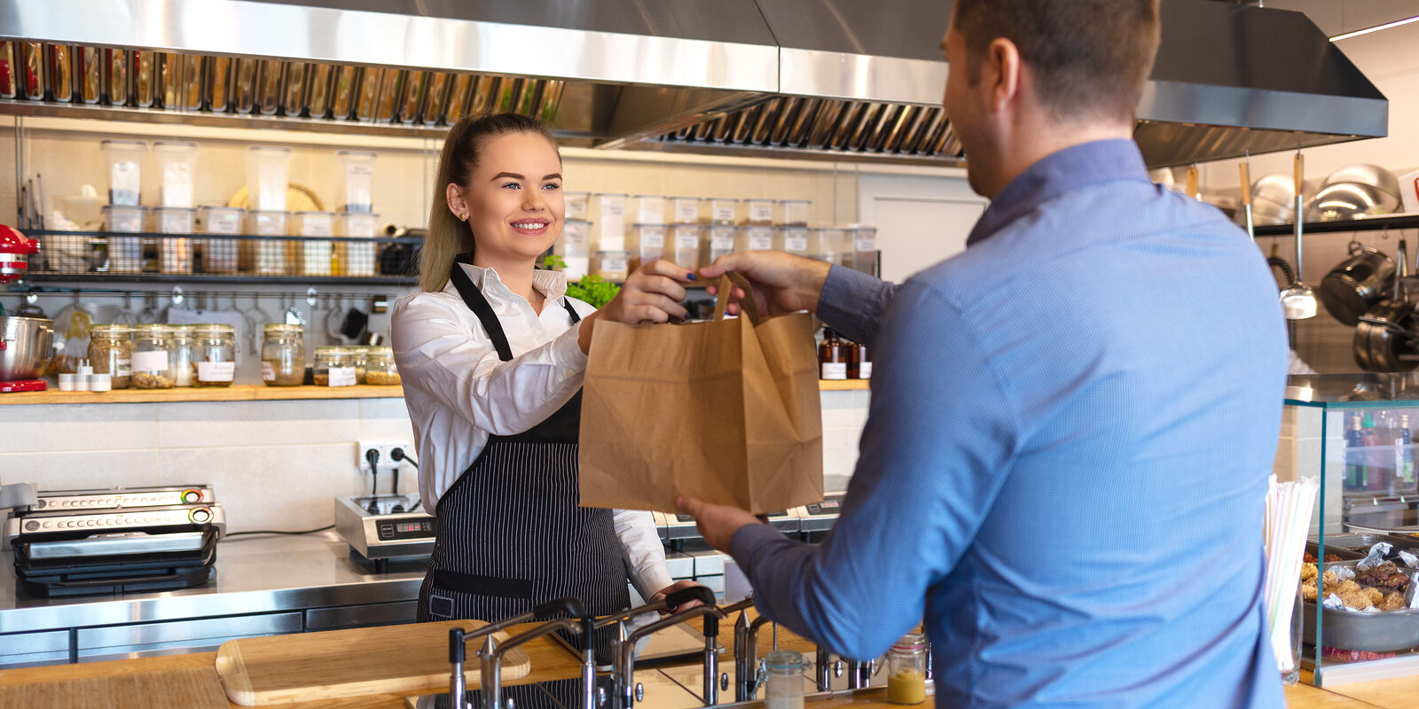 Smiling Young Waiter Giving Food Order To Man Client At Small Fa