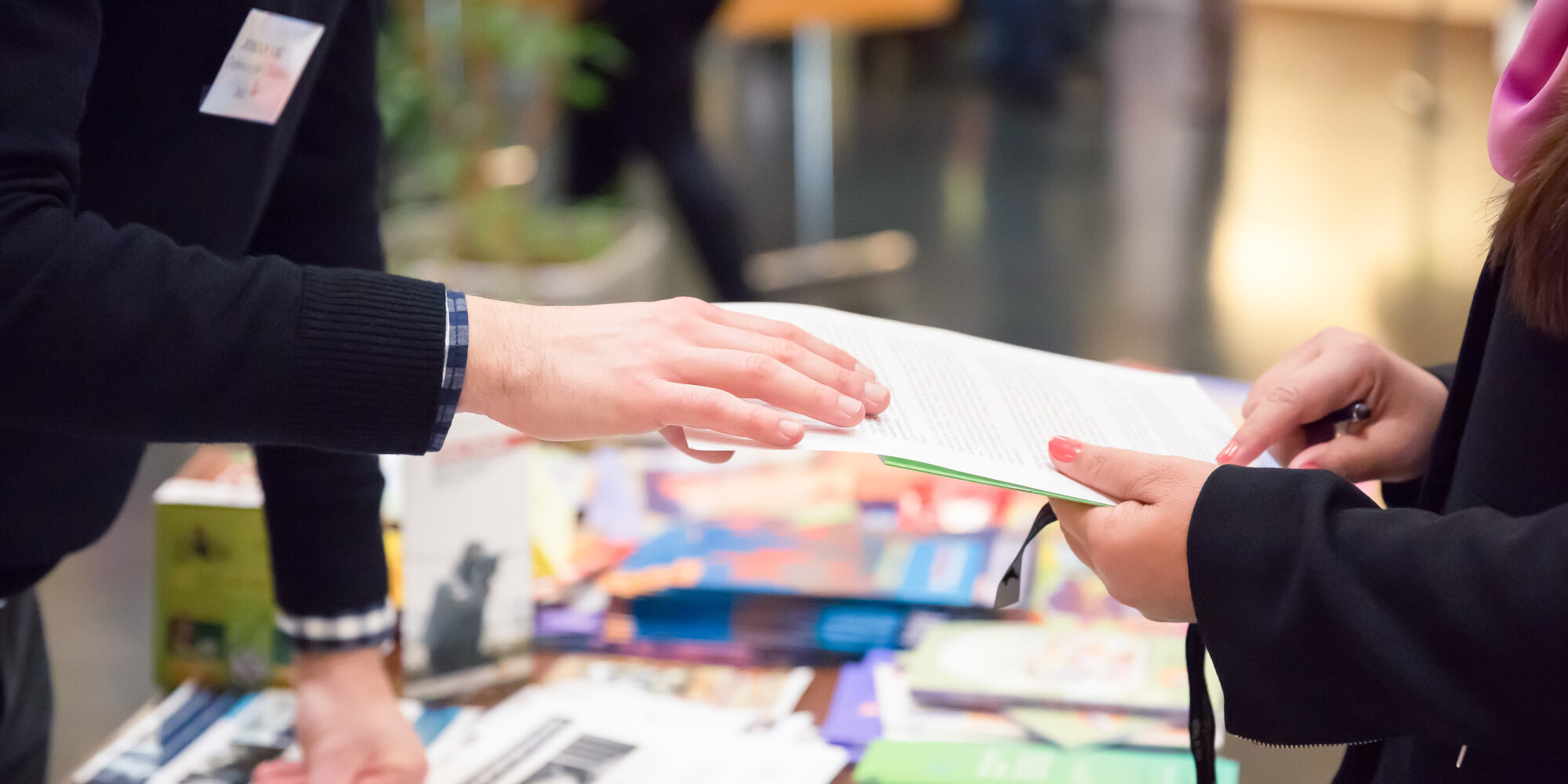Man and Woman Sharing Information Leaflet over Exhibition Stand.
